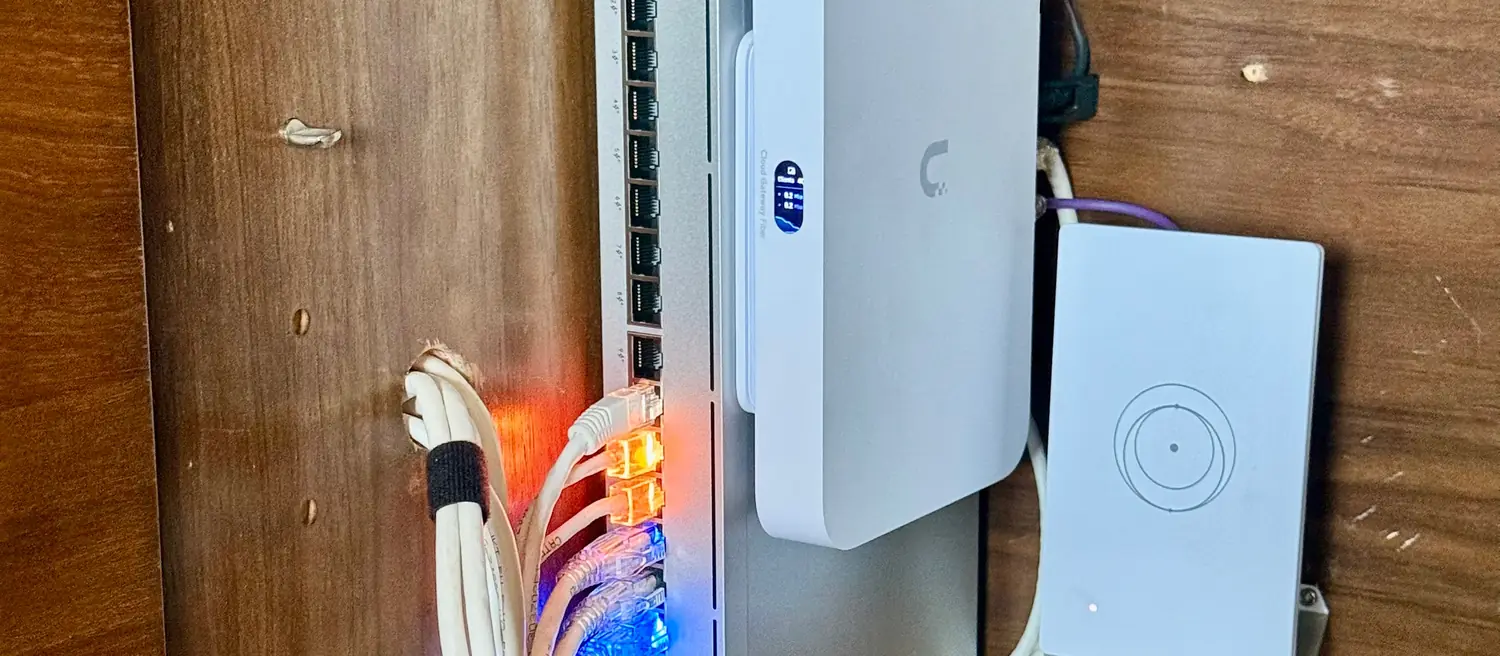 UniFi switch and gateway mounted upright in a wood cabinet