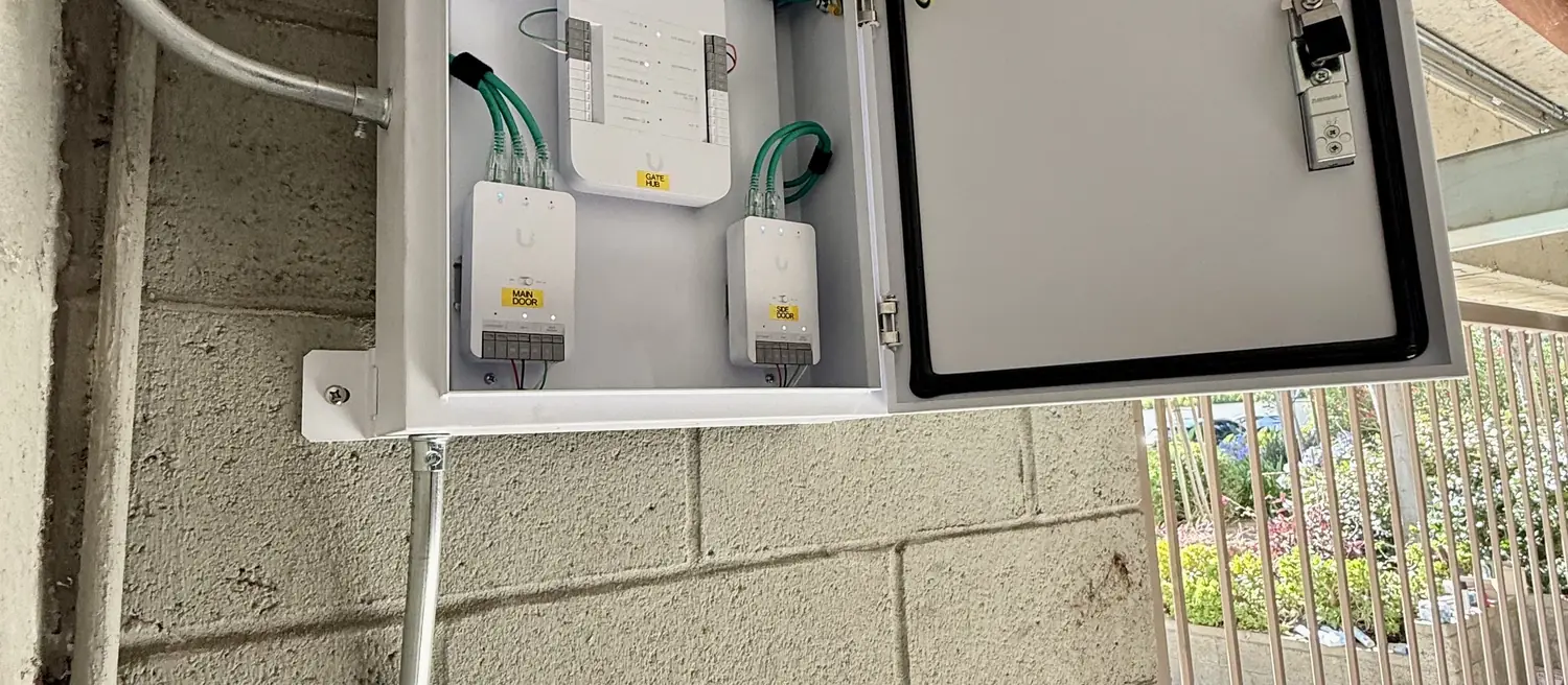 Three labeled UniFi Access hubs in a weatherproof enclosure