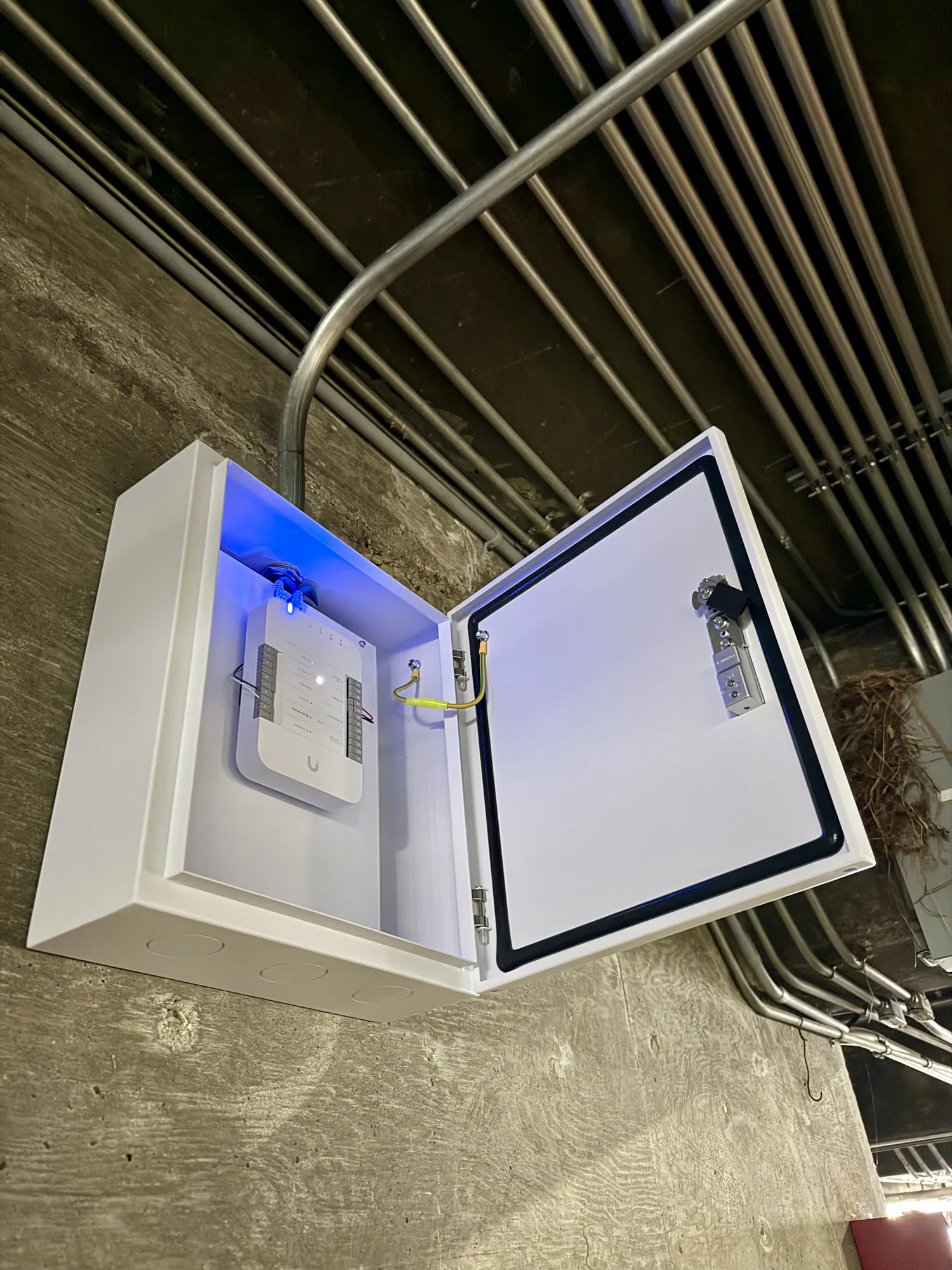 UniFi Access hub in a wall-mounted enclosure fed by conduit