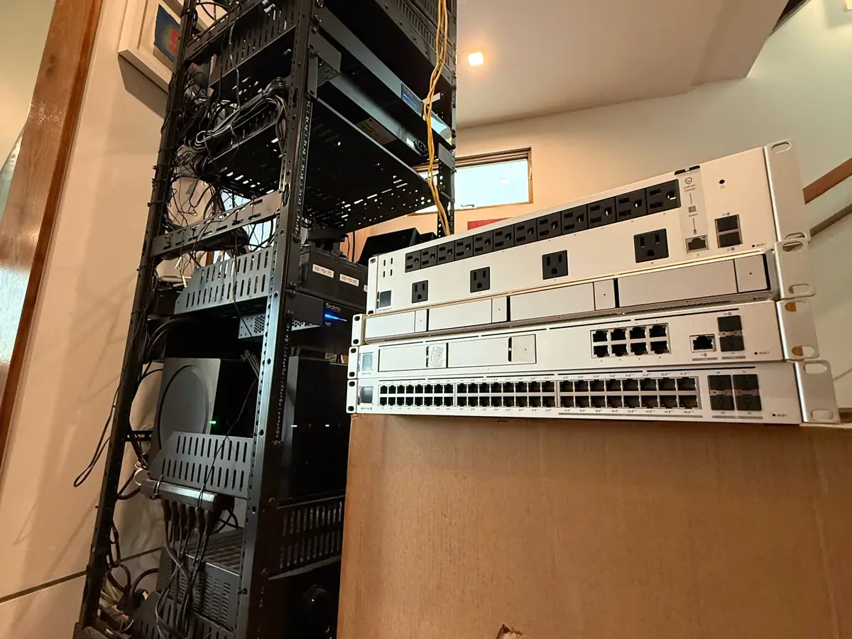 Old rack beside the staircase with new UniFi gear in front