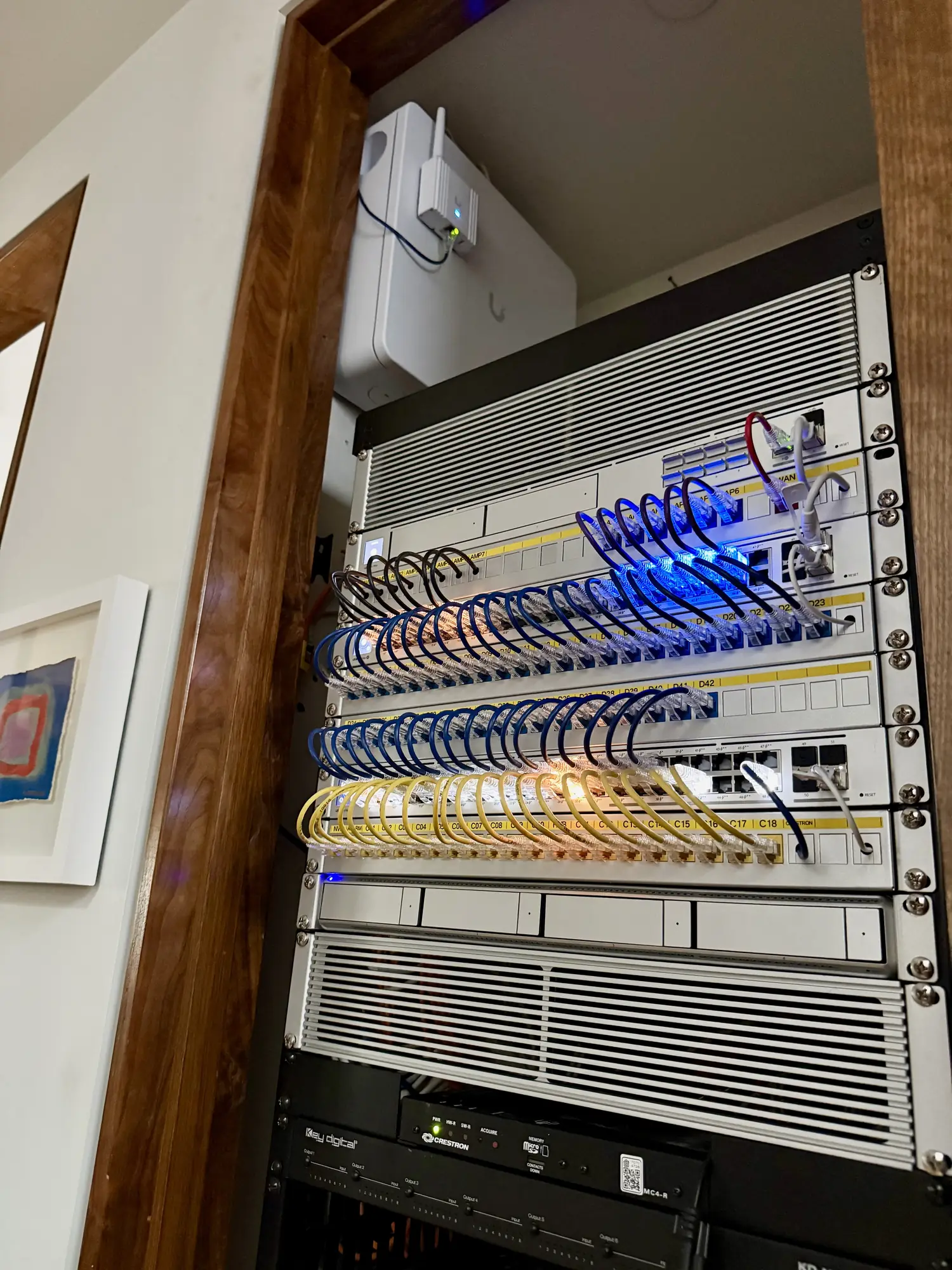 UniFi rack with patch panels in a wood framed alcove