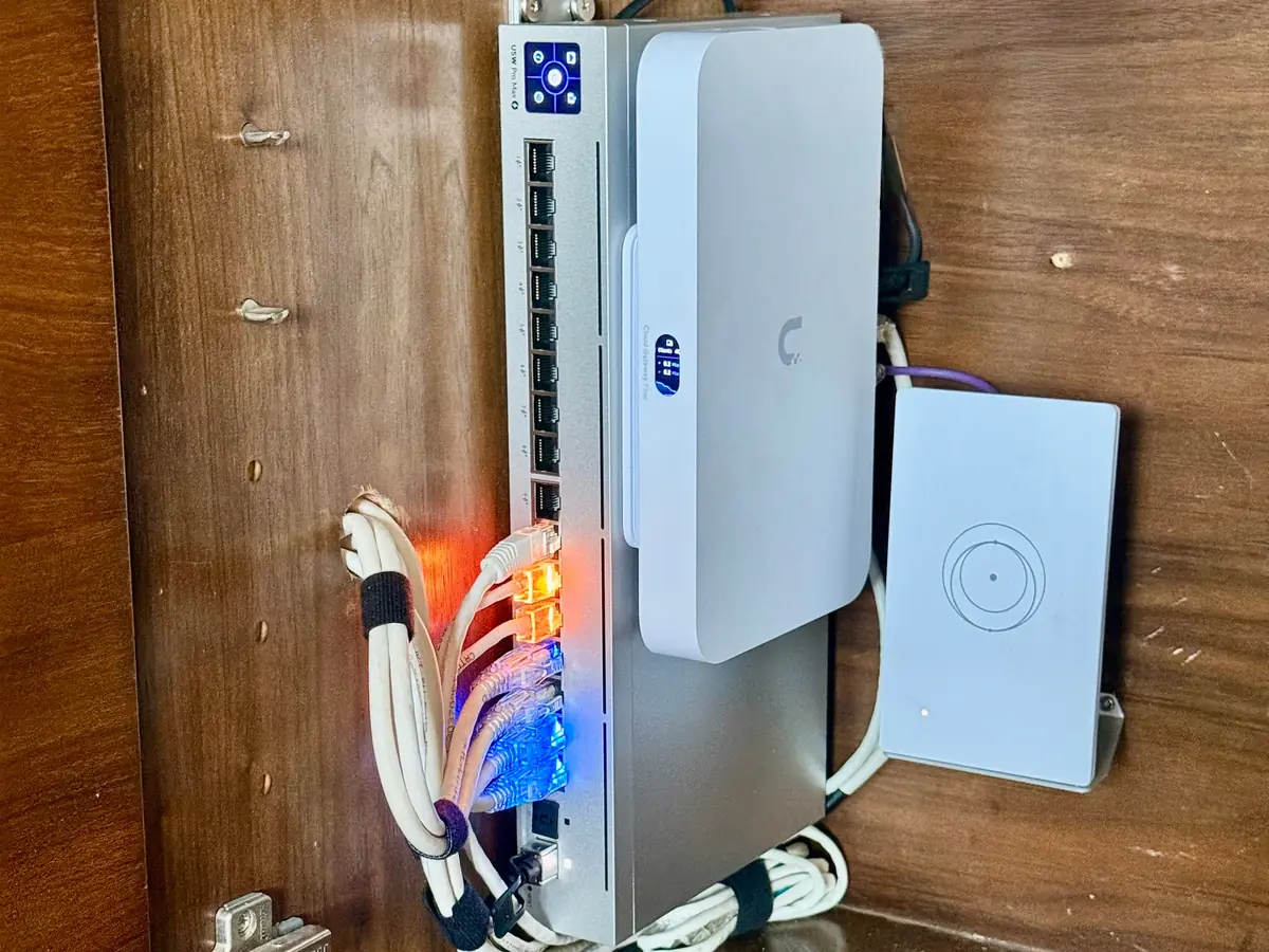 UniFi switch and gateway mounted upright in a wood cabinet