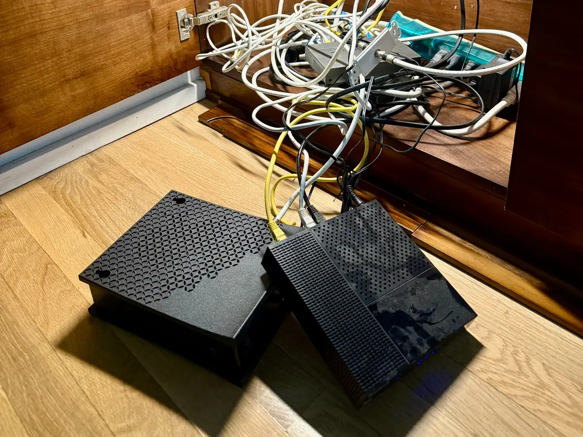 Modems and loose cable on the floor of a wood cabinet