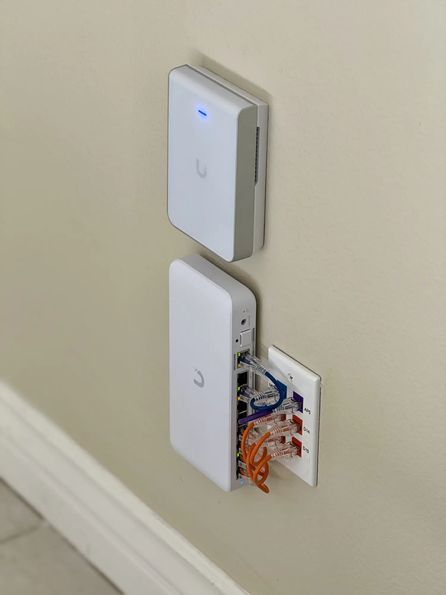 UniFi in-wall access points beside a labeled patch plate