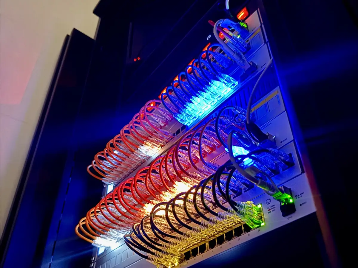 Equipment rack with lit patch cables above Sonos amplifiers