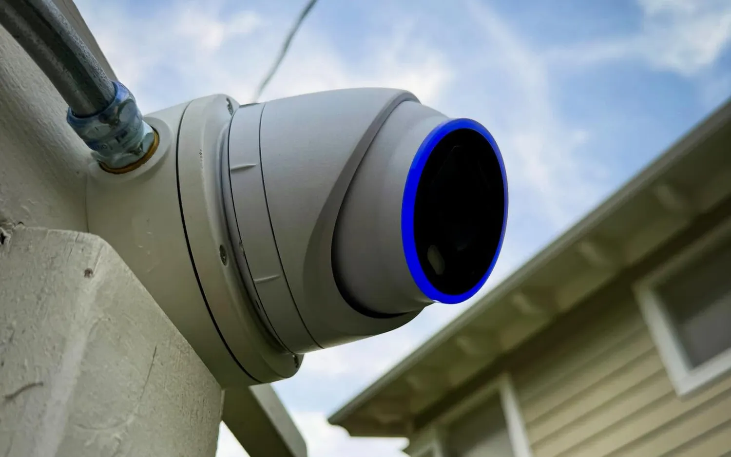 UniFi AI Turret camera on an exterior wall, fed through metal conduit
