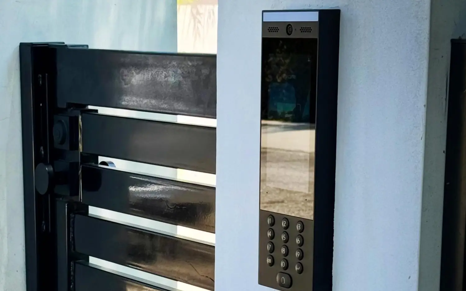 UniFi G3 Intercom on a white gate pillar next to a slatted metal gate