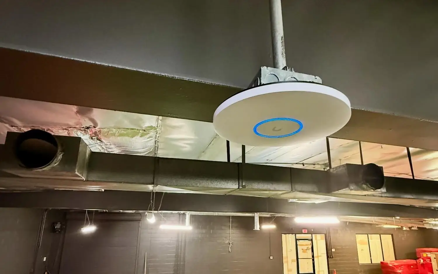 UniFi access point hanging from a pole in a gym