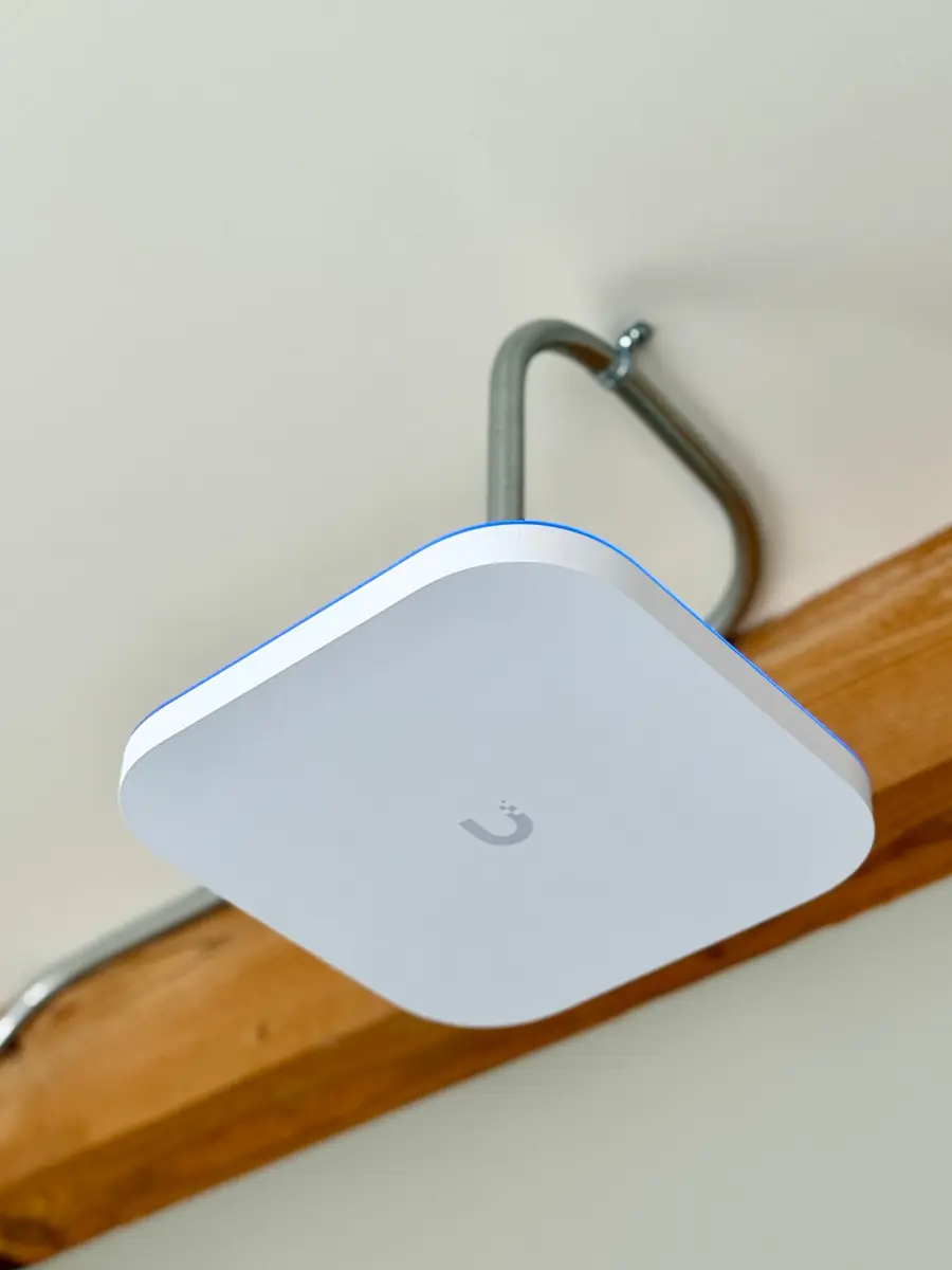 UniFi access point on a conduit mount below a white ceiling