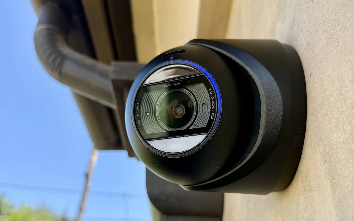 Black UniFi G6 Pro Turret camera mounted on a stucco wall beside a downspout
